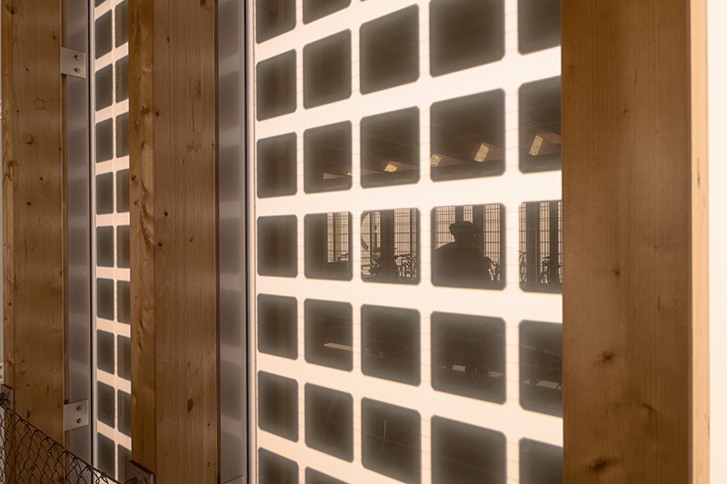 Nahe Aufnahme der abgerundeten quadratischen Solarpanels, die in die milchig-trüben Scheiben der Glasfassade eingebettet sind. 